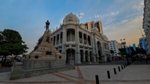 Fachada lateral del Palacio Municipal de Guayaquil con su cúpula característica y monumento en la Plaza de la Administración.