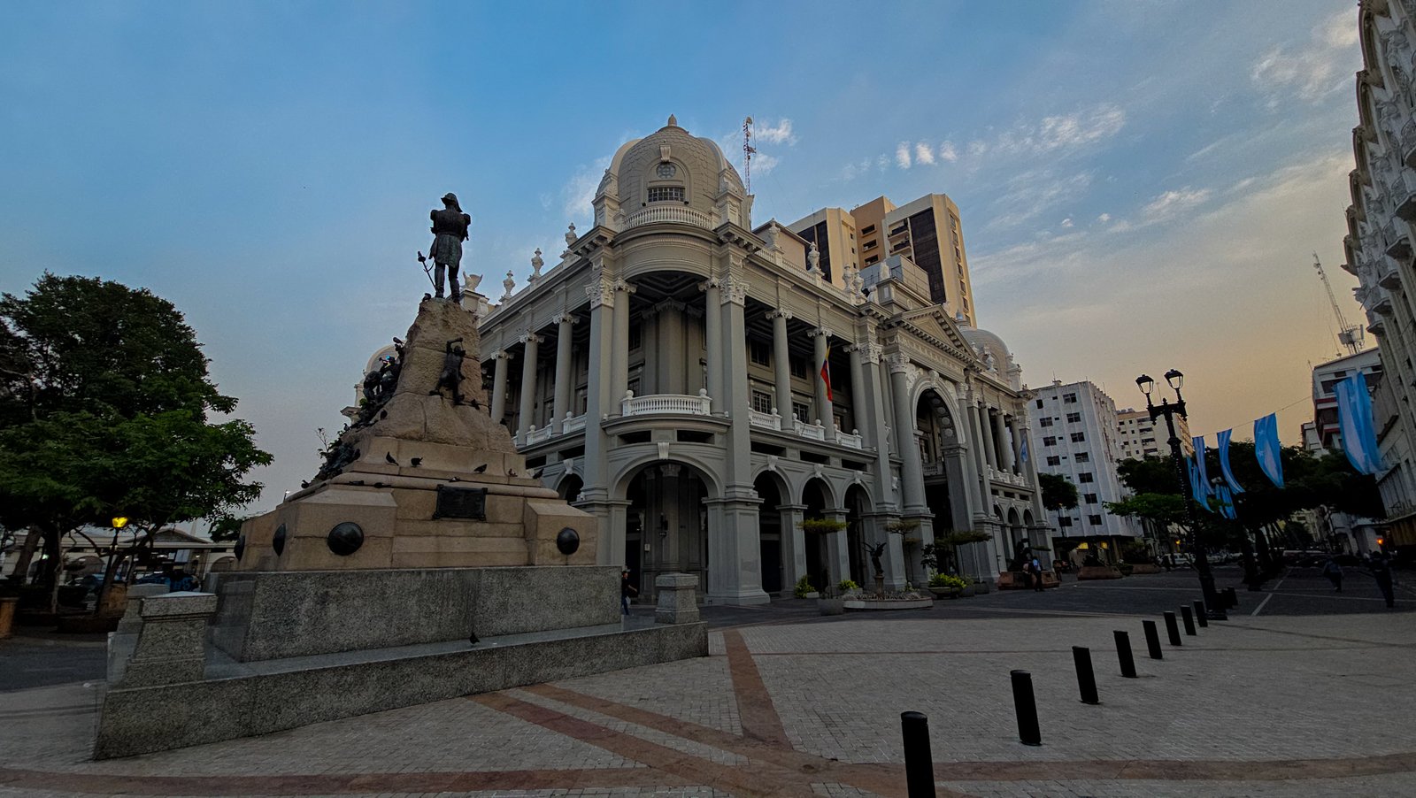 Fachada lateral del Palacio Municipal de Guayaquil con su cúpula característica y monumento en la Plaza de la Administración.