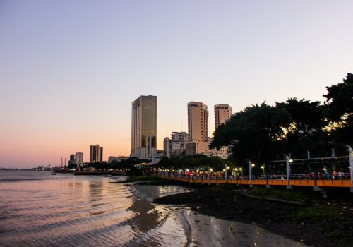 Vista panorámica del Malecón 2000 al atardecer con edificios modernos y el río Guayas en Guayaquil, Ecuador.